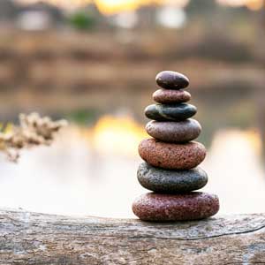 Galets empilés en équilibre au bord de l'eau illustrant la sérénité et la gestion du stress.
